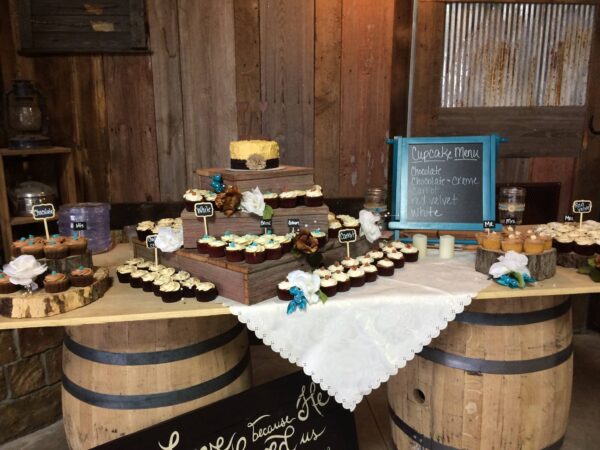 A table with cupcakes and cupcakes on top of barrels.