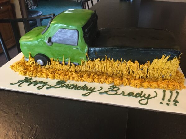 A birthday cake with a green truck on it.