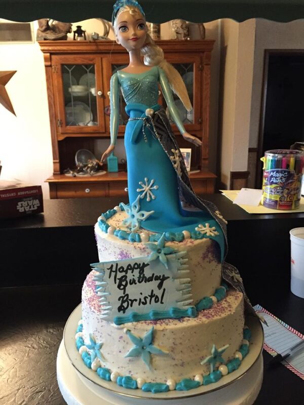 A cake with a frozen princess on top.