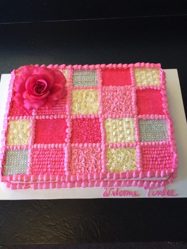 A pink and white cake with a pink flower on top.