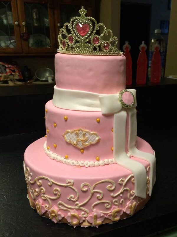 A pink cake with a princess tiara on top.