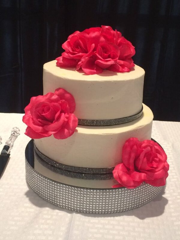 A white cake with pink flowers on top.