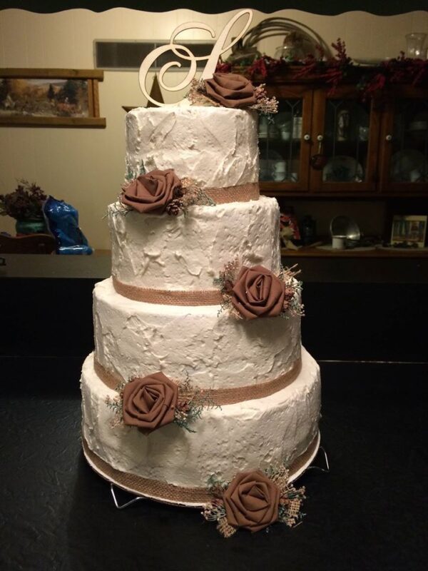 A three tier wedding cake with brown roses on top.