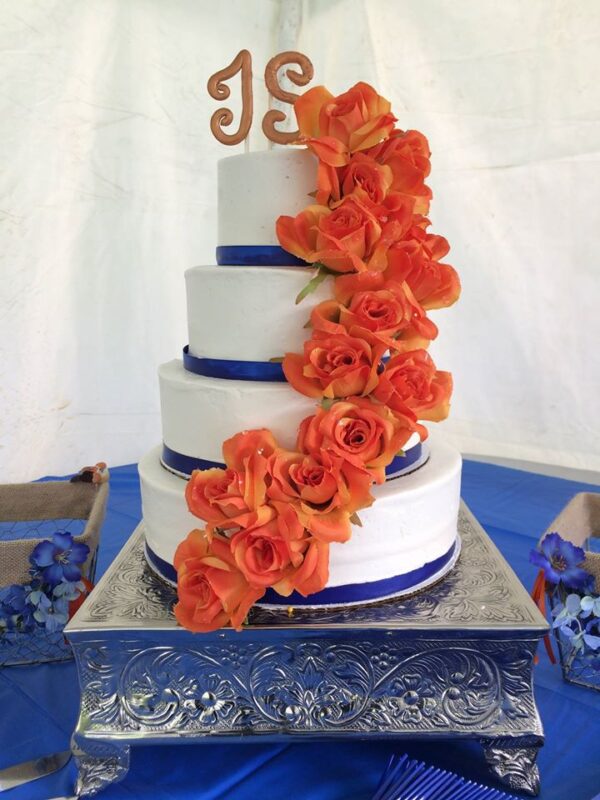 A three tier wedding cake with orange roses.