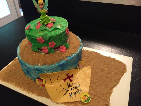 A cake with a tinker bell on top.