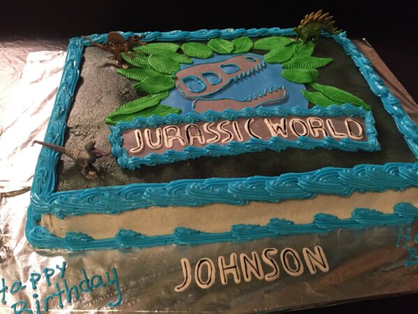 A blue cake with the words jurassic world on it.