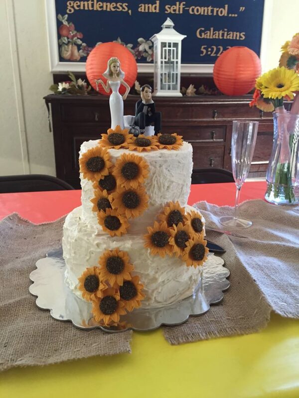 A wedding cake with sunflowers on top.