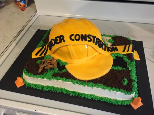 A cake with a construction hat on it.