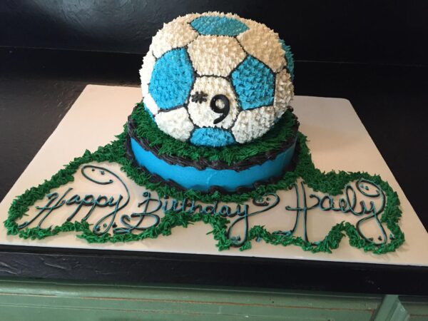 A cake with a soccer ball on top.