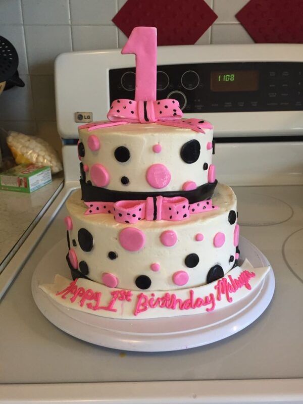 A pink and black cake with polka dots on top.