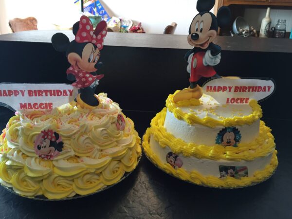 Two mickey mouse birthday cakes on a table.