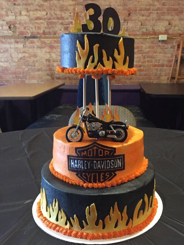 A harley davidson cake with a motorcycle on top.