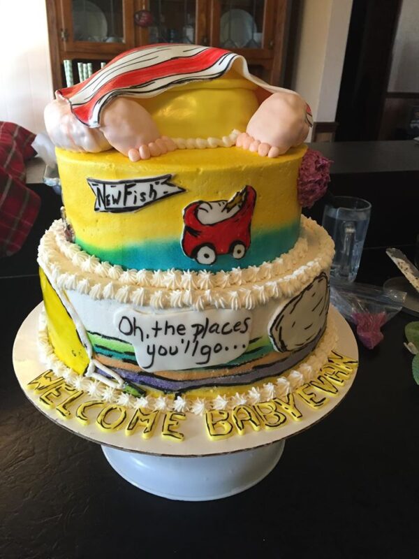 A cake with a baby sitting on top of it.