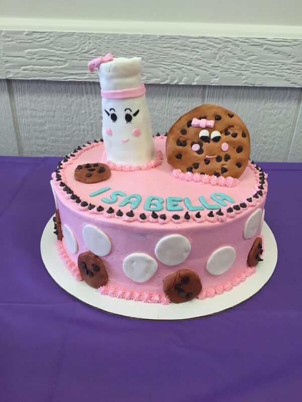 A pink cake decorated with cookies and milk.