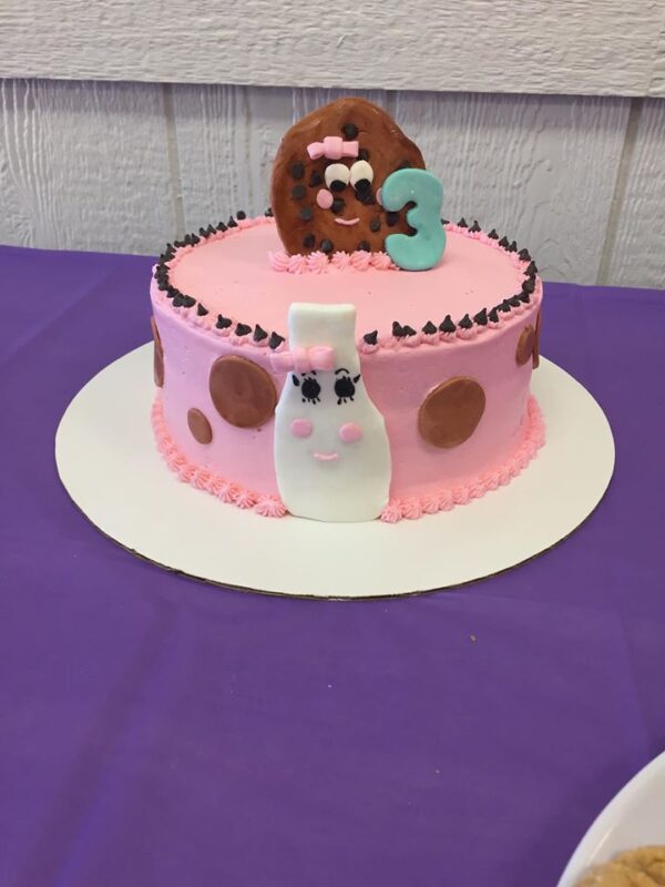 A pink cake with a donut on top.