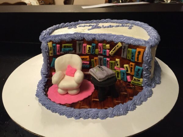 A cake with a chair and books.