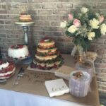 A table with different cakes and flowers.