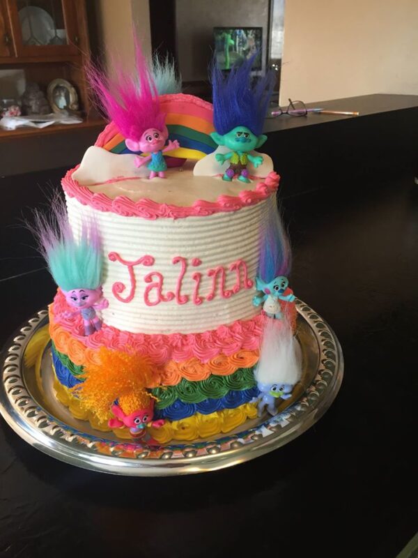 A cake decorated with trolls and rainbows.