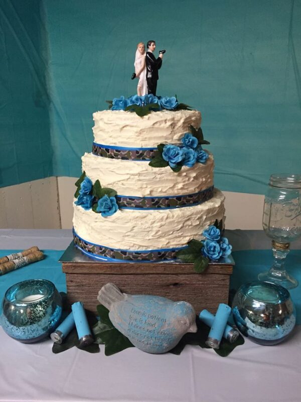 A three tier wedding cake with blue flowers.