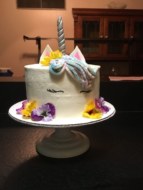 A unicorn cake with flowers on top.