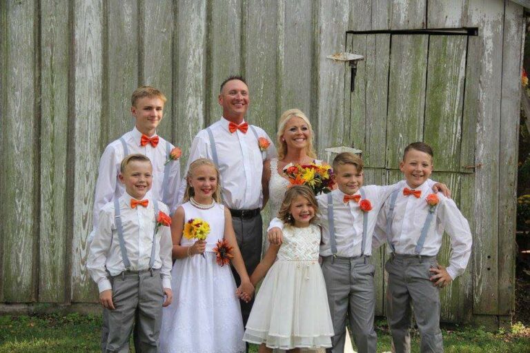 A group of people posing for a picture in front of a barn.