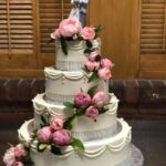 A wedding cake with pink flowers on top.