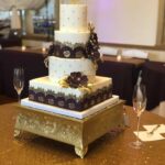 A purple and gold wedding cake on a table.