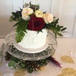 A white cake with red and white flowers on top.