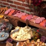 An assortment of meats and cheeses on a wooden table.