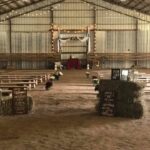 A barn with hay bales and benches for a wedding ceremony.