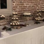 A table full of cupcakes and desserts on a brick wall.