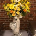 An arrangement of yellow flowers and silverware on a table.