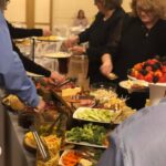 A group of people grabbing food from a buffet table.