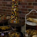 A buffet of appetizers and desserts with a christmas tree in the middle.