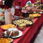 A table full of food on a red tablecloth.