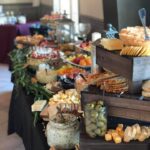 A buffet table with a variety of cheeses and crackers.