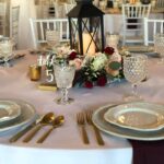 A table setting with gold and burgundy plates and silverware.