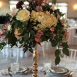 A centerpiece with gold and white flowers on a table.