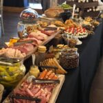 A buffet table with a variety of meats and cheeses.