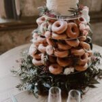 A wedding Tiered Cakes with donuts on top of it.