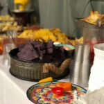 A buffet table with chips, salsa, and other snacks.