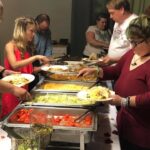 A group of people serving food at a buffet.