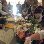 A group of people serving food at a buffet.