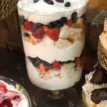 A trifle with whipped cream and berries on a table.