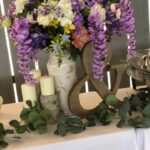 An arrangement of purple flowers and greenery on a table.