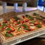 A tray of strawberries and basil on a table.