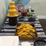 A table with chips, salsa, and an umbrella.