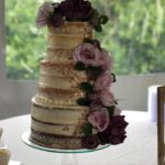 A wedding cake with purple flowers on top.