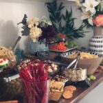 A buffet with a variety of snacks and flowers.