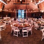 A large barn with tables and chairs set up for a wedding reception.